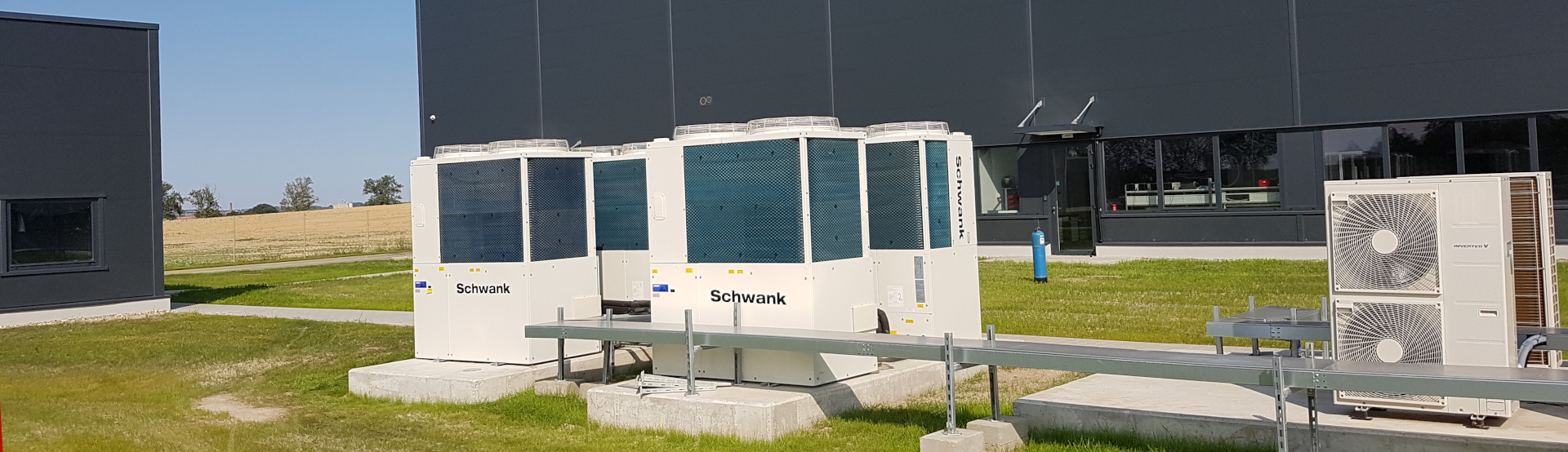 Four gas heat pumps from Schwank in front of an industrial building.